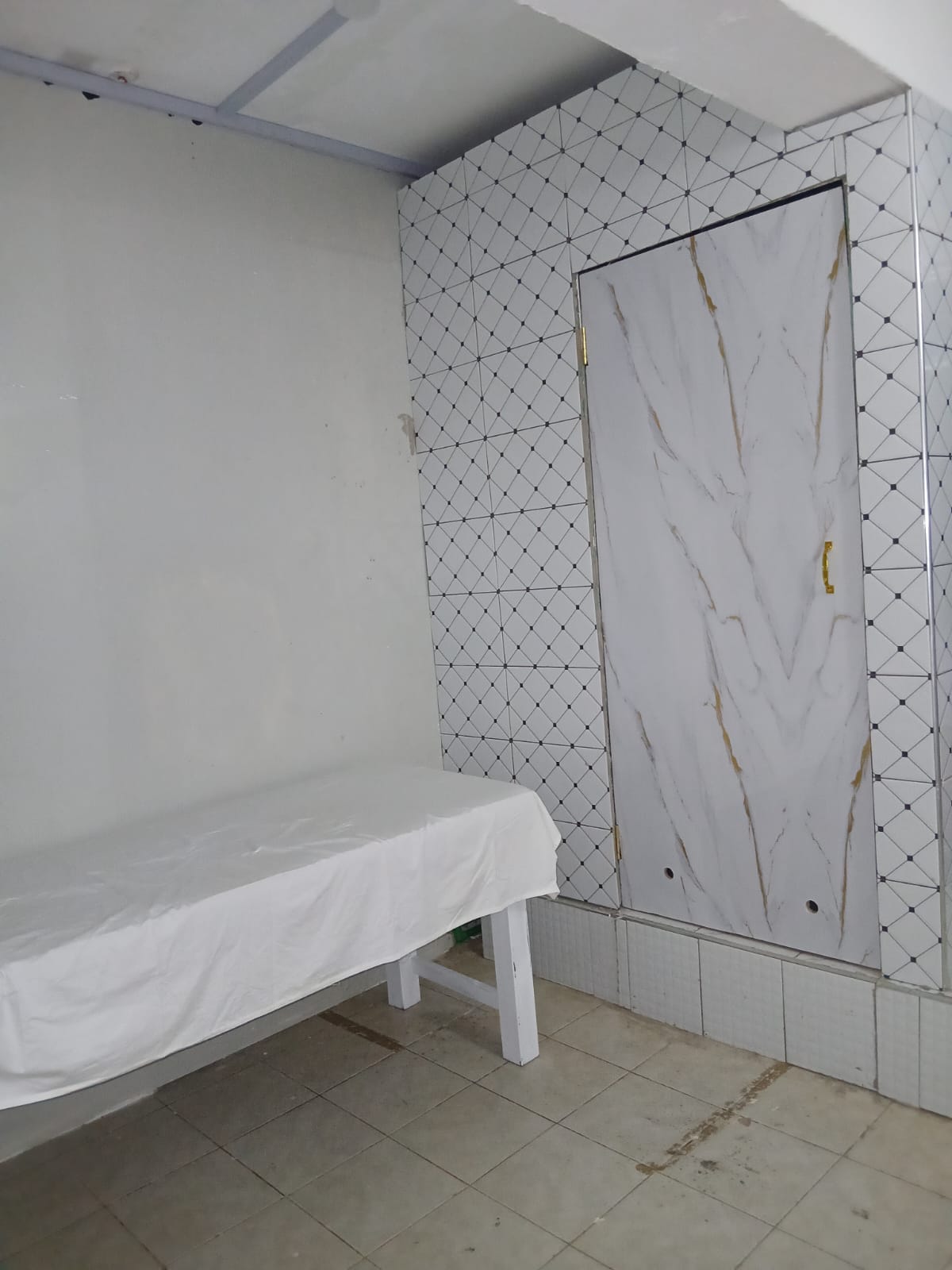 White-tiled massage room with marble door