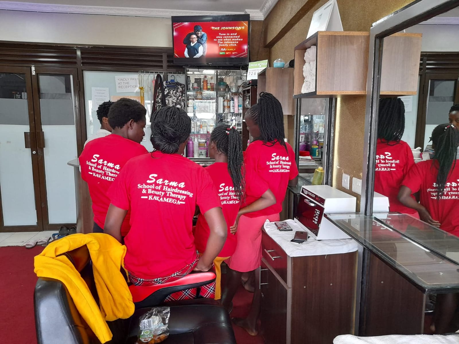 Sarma School students in branded red uniforms training on the salon floor